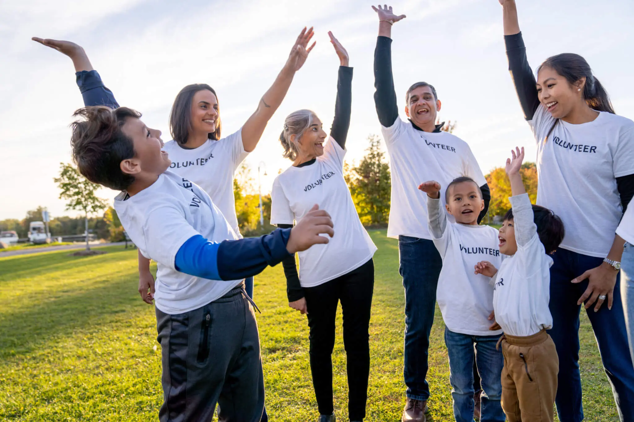 Group of volunteers raising hands outdoors