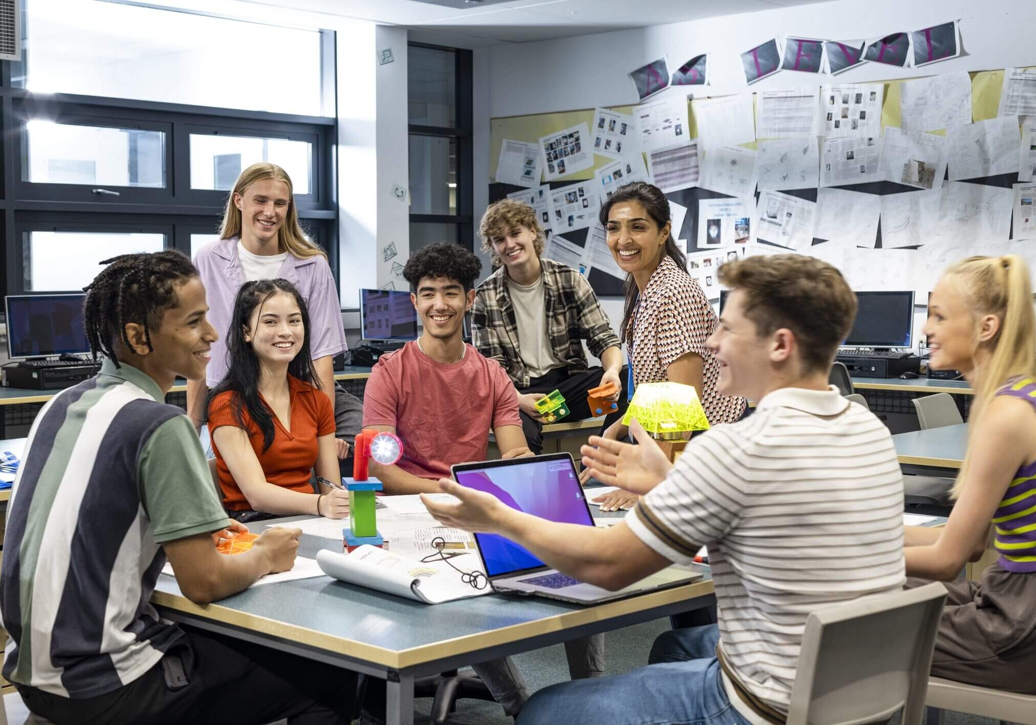 A diverse group of young adults collaborating around a table in a bright workspace.