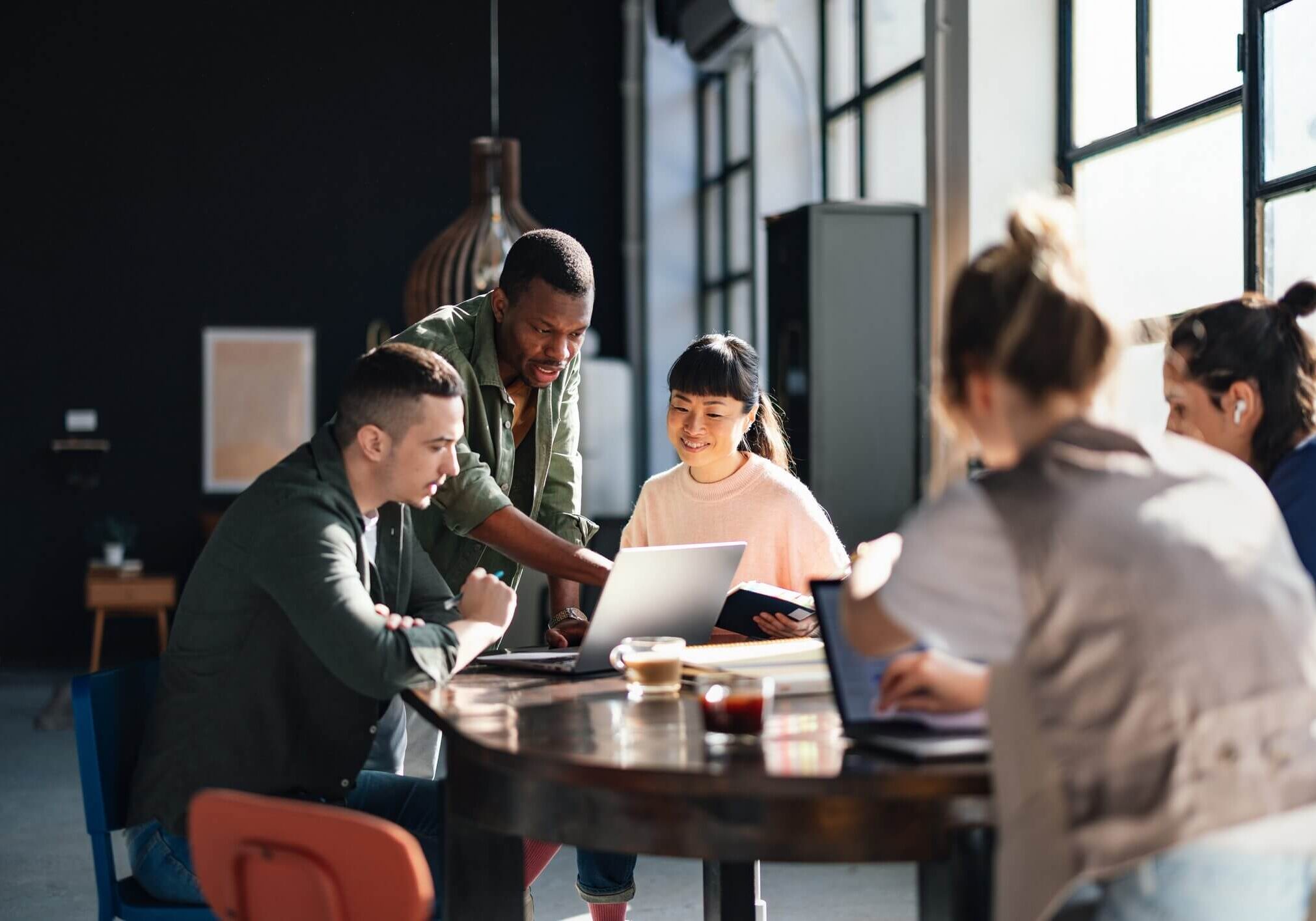 Diverse team collaborating around a table in a modern office space.