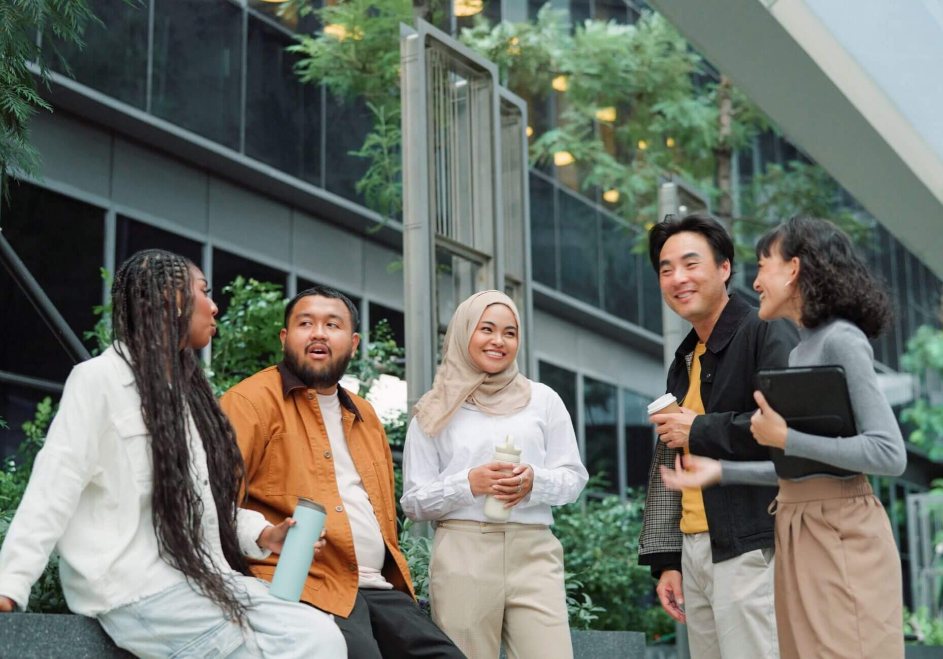 A group of diverse friends chatting outdoors in a modern urban setting.
